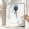 Art print of Dallas Reunion Tower in a white frame held by a hand, with a vase and dried flowers nearby.