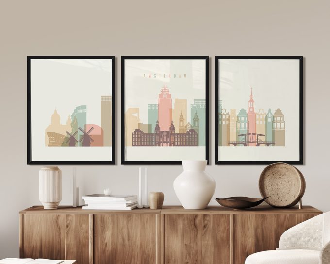 Three framed art prints depicting a stylized cityscape of Amsterdam with buildings and windmill.