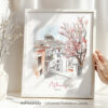Hand holding a framed art print of Athens in watercolor drawing with soft pastel tones.