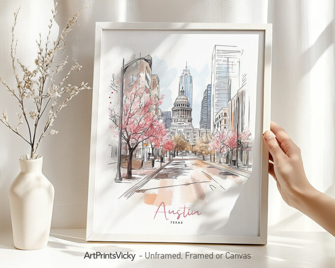 Hand holding a framed art print of Austin in watercolor drawing with soft pastel tones.