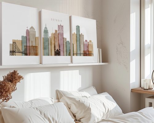 Three art prints of Detroit's skyline displayed above a bed with white bedding.