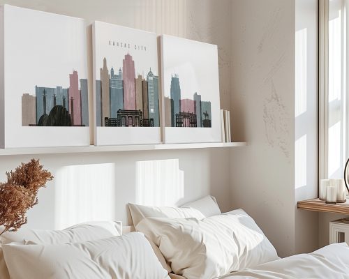 Three art prints depicting the skyline of Kansas City displayed above a bed with white bedding.