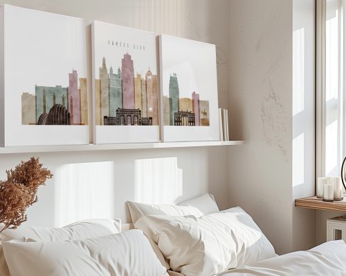Three art prints of Kansas City skyline in muted colors displayed above a bed.