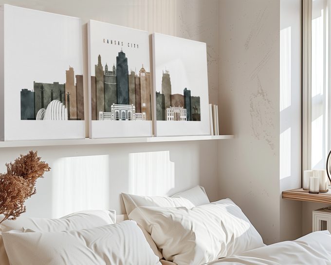 Three canvas artworks depicting the skyline of Kansas City displayed on a shelf above a bed.