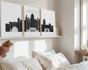 Three black and white art prints of the Kansas City skyline displayed on a shelf above a bed.
