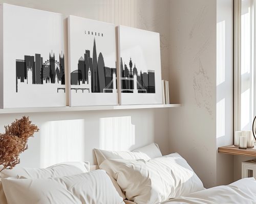 Three black and white art prints of the London skyline displayed on a shelf above a bed.