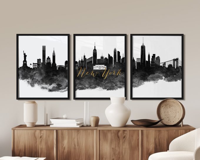 Three framed art prints of the New York City skyline with black and white design and gold text.