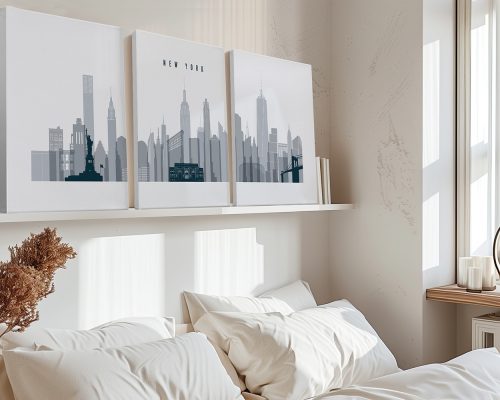 Three canvas prints of the New York City skyline in grayscale displayed on a shelf above a bed.