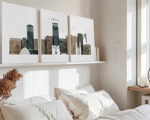 Three framed art prints depicting the cityscape of Omaha displayed above a bed.