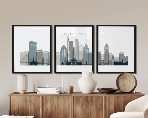Three framed prints of the Philadelphia skyline displayed on a wooden surface.