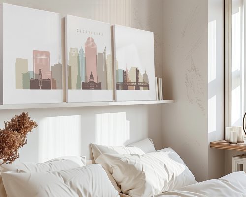 Three framed art prints of Sacramento's skyline displayed on a shelf above a bed.