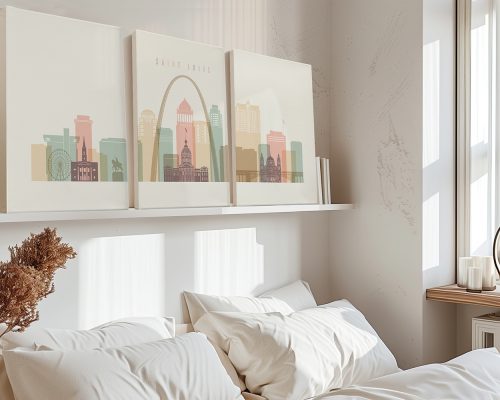 Three framed artworks depicting a stylized cityscape of Saint Louis on a shelf above a bed.
