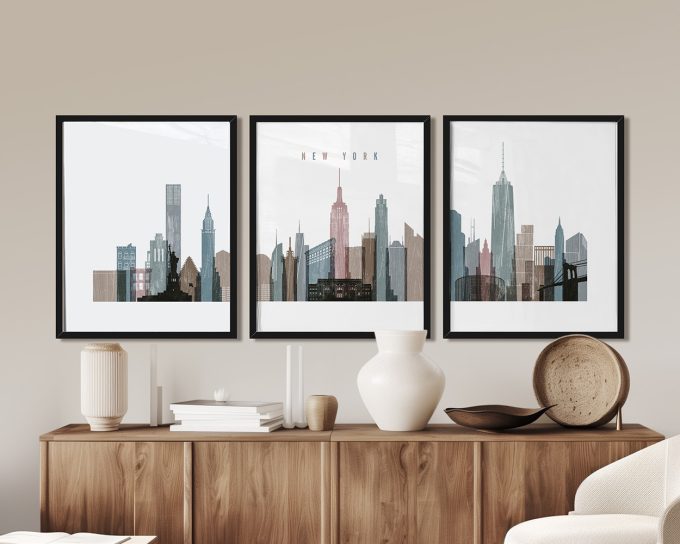Three framed prints of New York City skyline in various colors and styles displayed on a wall.