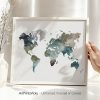 Watercolor map of the world in shades of blue and green displayed in a frame.