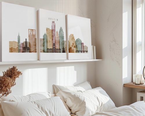 Three art prints of Austin's skyline displayed on a shelf above a bed with white bedding.