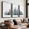 Three framed art prints of the Austin city skyline displayed on a wall above a couch.
