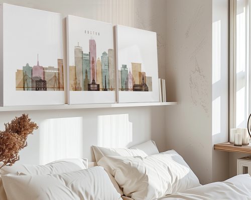 Three framed art prints of Boston's skyline displayed on a shelf above a bed.