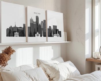 Three black and white art prints depicting the skyline of Boston on a shelf above a bed.