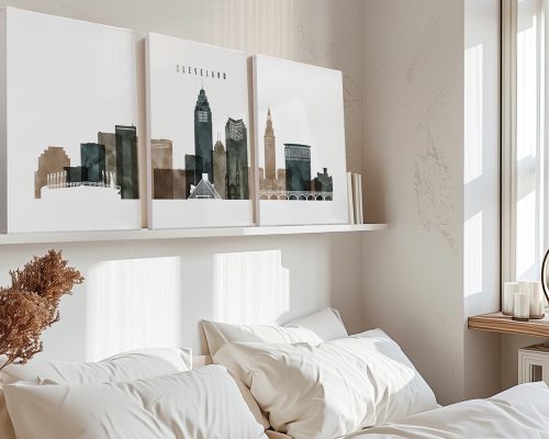 Three art prints of Cleveland's skyline displayed above a bed in a neutral-colored room.