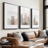 Three framed art prints of a Denver cityscape displayed on a wall above a couch.