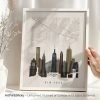 Framed print of a New York City skyline with a map background in neutral colors.