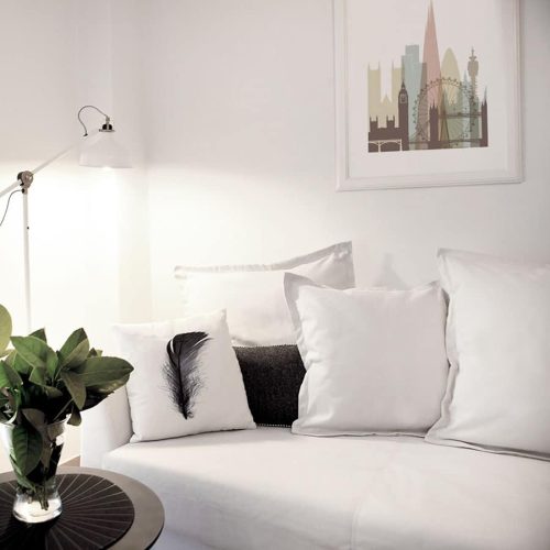 A white couch with decorative pillows and a small plant on a side table.