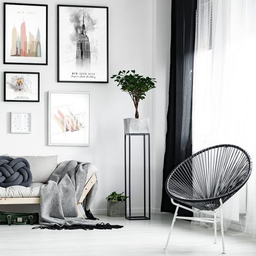 A modern living room featuring framed artwork, a plant, and a stylish chair.