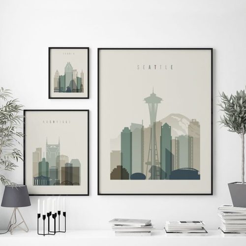 Framed prints of Seattle and Nashville cityscapes displayed on a wall with decorative elements.