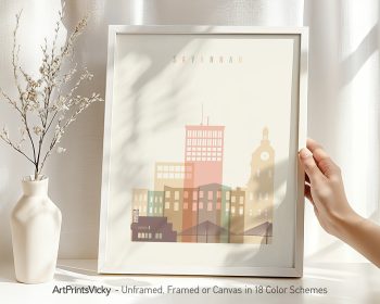 Framed artwork depicting a stylized cityscape of Savannah with pastel colors and geometric shapes.