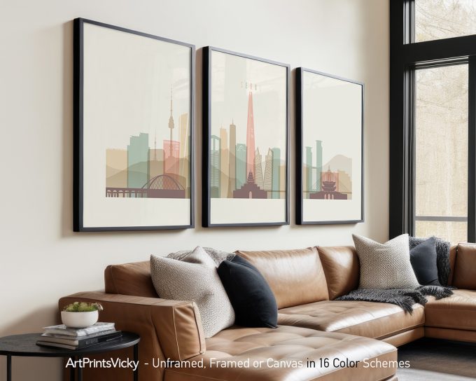 Three framed cityscape artworks displayed on a wall above a couch in neutral tones.