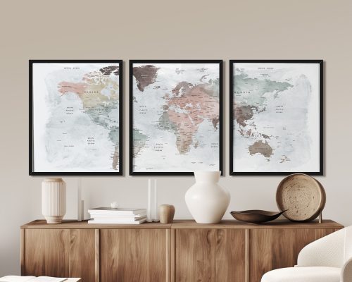 Three framed world maps in pastel tones displayed on a wooden surface.