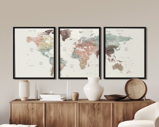 Three framed maps of the world with muted colors and labeled countries displayed on a wall.