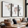 Three framed world maps displayed on a wall above a couch in a living room setting.