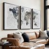 Three framed maps of the world in neutral colors displayed on a wall above a sofa.