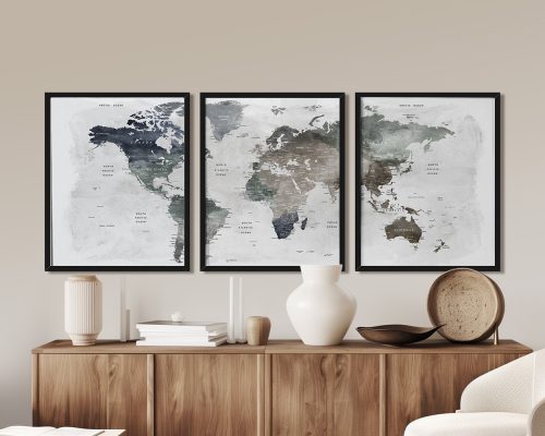 Three framed world maps with muted colors displayed on a wooden surface.